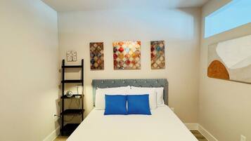 Un dormitorio con una cama, un ventilador de techo, un estante en la pared y obras de arte.