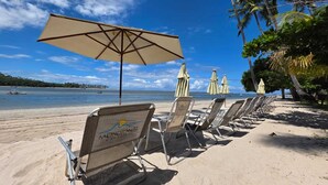 Ein Strand mit Reihen von Liegestühlen und einem großen Sonnenschirm.