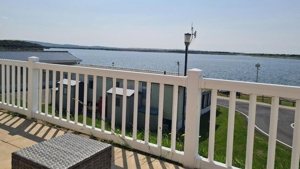 Une propriété située au bord de l’eau, avec une clôture blanche, un lampadaire et une vue sur l’eau.