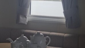 Une pièce avec une fenêtre donnant sur un plan d’eau, un canapé et une table avec une théière et des tasses.