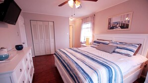 Een slaapkamer met een bed, een dressoir en een plafondventilator.