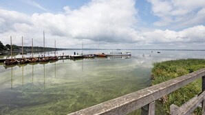 En rolig sø med fortøjede både, en træbrygge og et fjerntliggende horisontbillede.