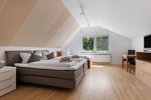 Une chambre à coucher avec un lit, des tables de chevet, un bureau et une fenêtre.