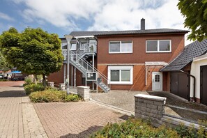 Un immeuble résidentiel de deux étages, doté d’une façade en briques, d’un escalier menant à l’étage supérieur et d’une porte de garage.