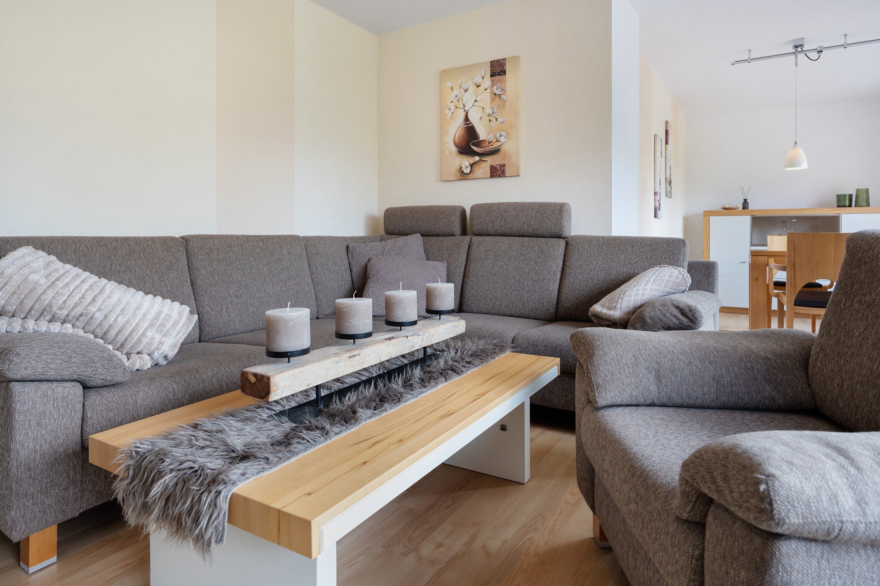 A modern living room with a grey sofa, a wooden coffee table, and a painting on the wall.