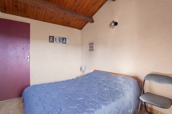 A bedroom with a bed, a chair, a door, and a wall with a sign that reads 'RELAY'.