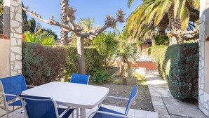 Une terrasse avec une table et des chaises, entourée de murs en pierre et de palmiers.