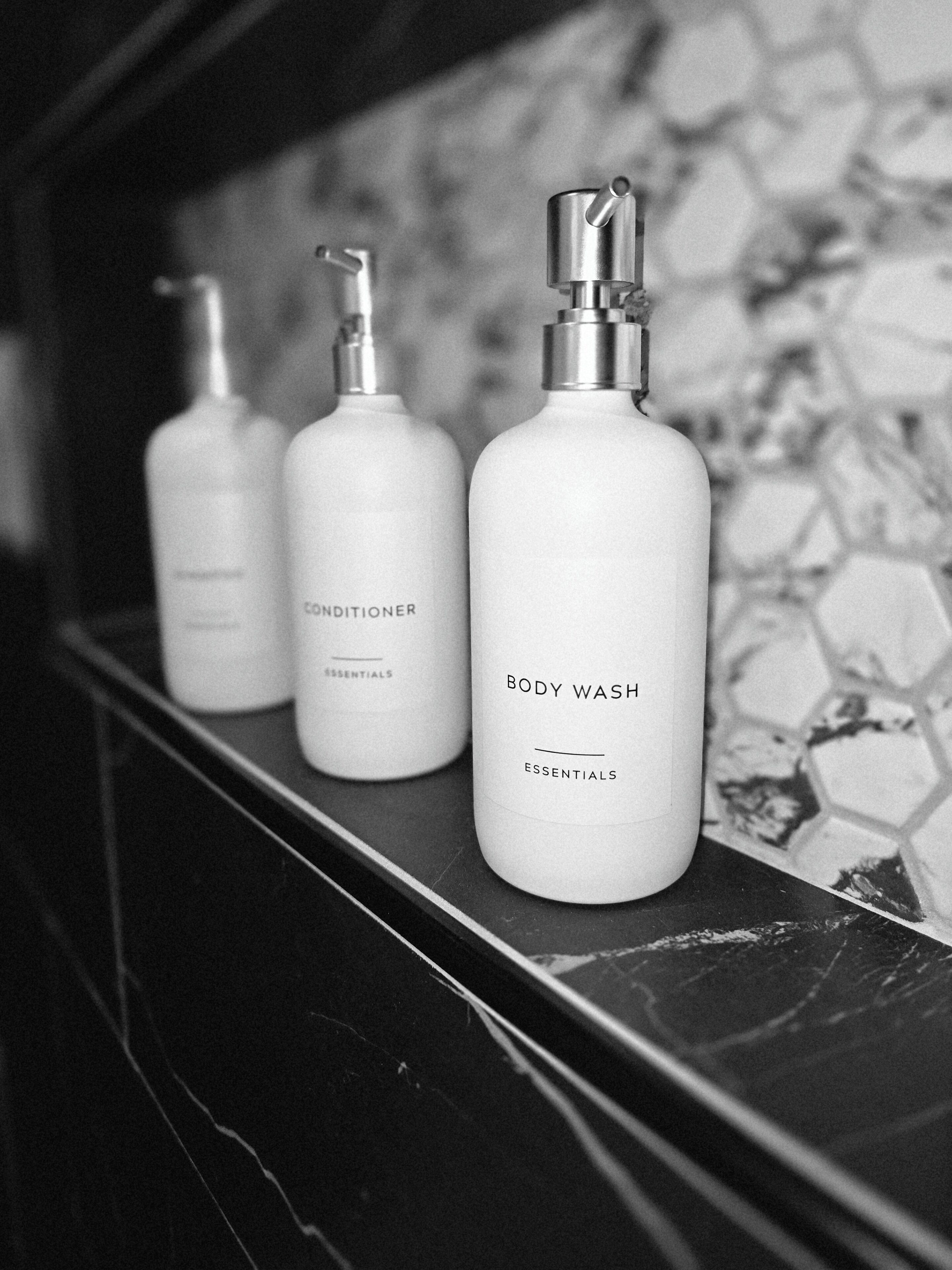 Three bottles of body wash and conditioner on a shelf.