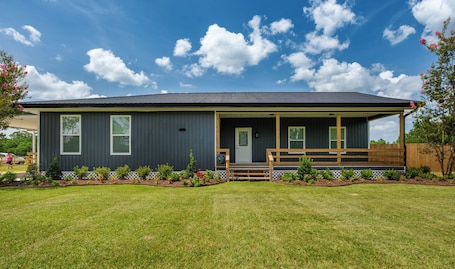 A modern two-story house with a covered porch, a front door, and a small garden area.