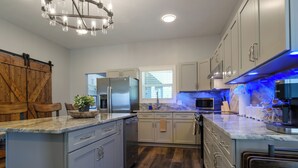 Una cocina moderna con una isla central, electrodomésticos de acero inoxidable y una puerta corrediza de estilo rústico.