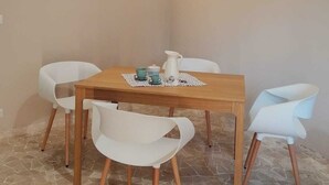 Ein Essbereich mit einem Holztisch, vier weißen Stühlen und einer Kaffeekanne.