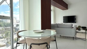 Ein modernes Wohnzimmer mit einem Glastisch, einer Couch und einem an der Wand montierten Fernseher.
