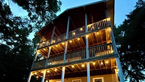 A two-story wooden building with a balcony on each floor, surrounded by trees.