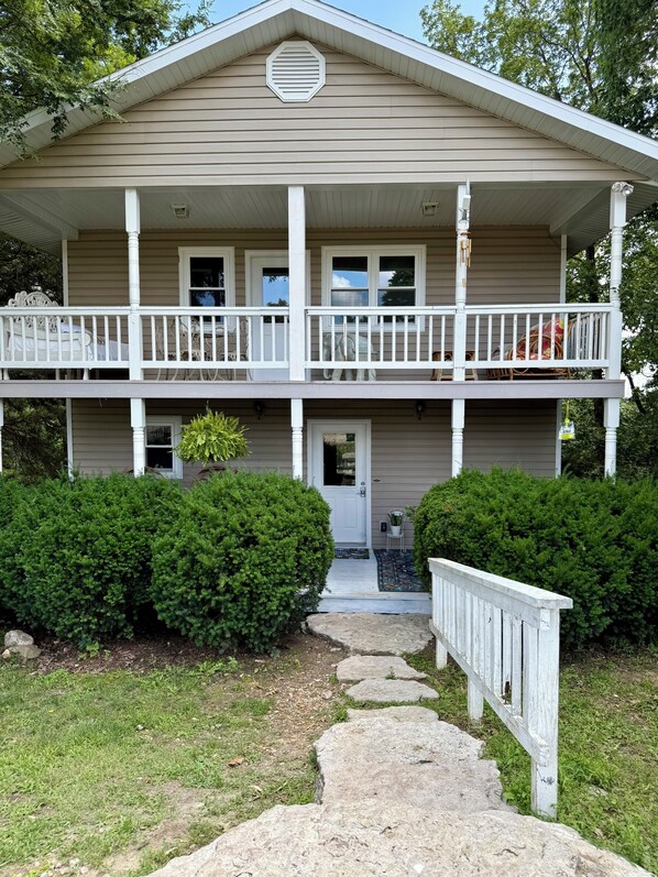 A two-story house with a front porch, a covered entryway, and a small front yard with a pathway leading to the door.