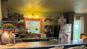 A kitchen with a central island, bar stools, a dog bed, and a decorative lamp.