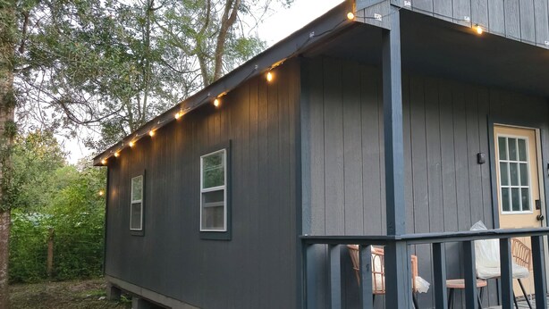 A small wooden cabin with a porch and string lights.