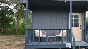 A small wooden structure with a door, two chairs, and a table on a deck.