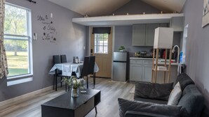 A compact living space with a dining area, kitchenette, and a gray sofa.