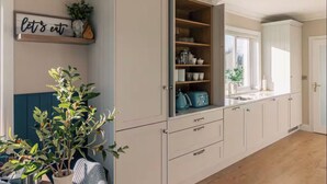 A kitchen with white cabinets, a window, and a 'let's eat' sign.