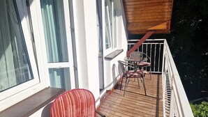 A balcony with a table and chairs, a wooden ceiling, and a white railing. - Comfortable Double Room by the Promenade (Międzyzdroje)