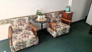 A corner room with floral-patterned armchairs, a small round table with a plant, and a kettle on a cabinet. - Comfortable Double Room by the Promenade (Międzyzdroje)