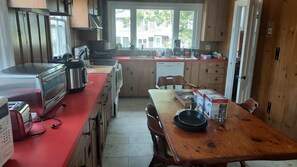 A kitchen with a red countertop, stainless steel appliances, and wooden cabinets.