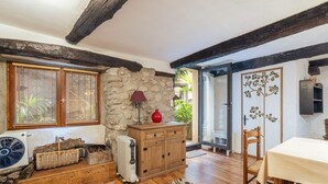 Un intérieur rustique avec un mur en pierre, des poutres en bois, une table à manger et un radiateur.