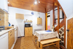 Une cuisine compacte dotée de meubles en bois, d’un four à micro-ondes, d’un évier et d’un coin repas avec un banc.