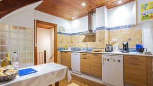 Une cuisine avec des meubles en bois, un lave-vaisselle blanc et une table sur laquelle se trouve un classeur bleu.