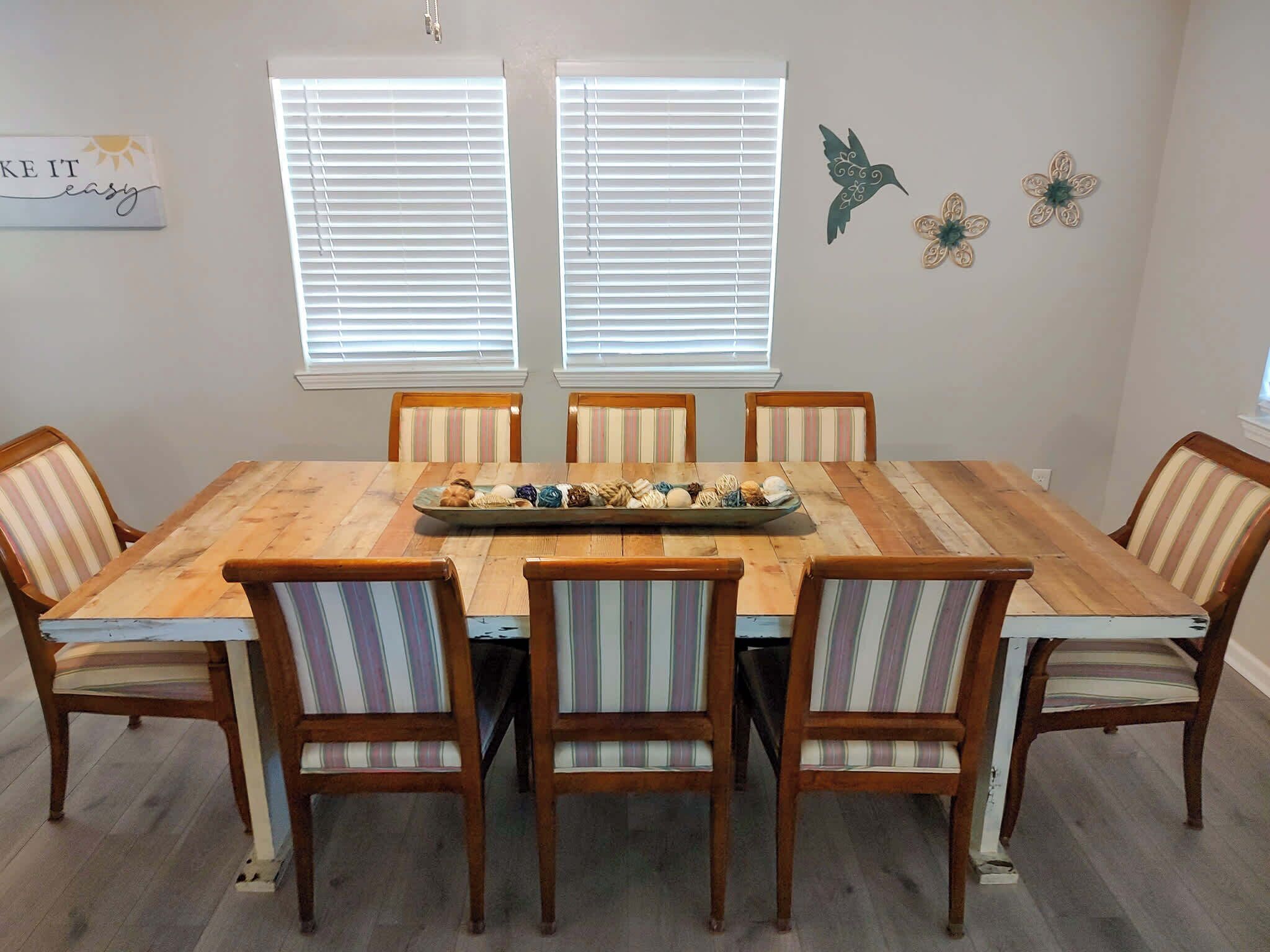 A dining area with a wooden table, six striped chairs, and decorative wall art.
