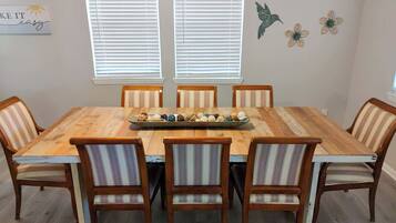 A dining area with a wooden table, six striped chairs, and decorative wall art.