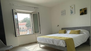 Een slaapkamer met een bed, een stoel, een raam en een plafondlamp.