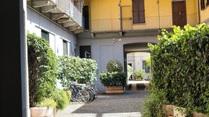 Un patio con un sendero de grava, plantas en macetas y bicicletas.