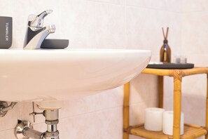 A bathroom sink with a modern faucet, a bamboo shelf with toiletries, and a wall-mounted towel rack. - La Milanesina - One Bedroom Apartment, Sleeps 4 (Milan)