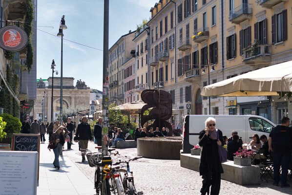 A bustling urban street with pedestrians, bicycles, and outdoor seating at cafes.