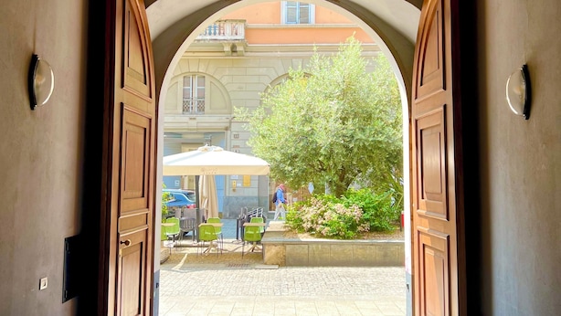 Un arco de entrada que da a un área exterior con mesas y sillas.