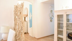 A room with a wooden floor, a white cabinet with glass doors, a blue-striped door, and a decorative wall piece. - LuMa Suite Spanish-Trevi Via degli Artisti 23 (Roma)