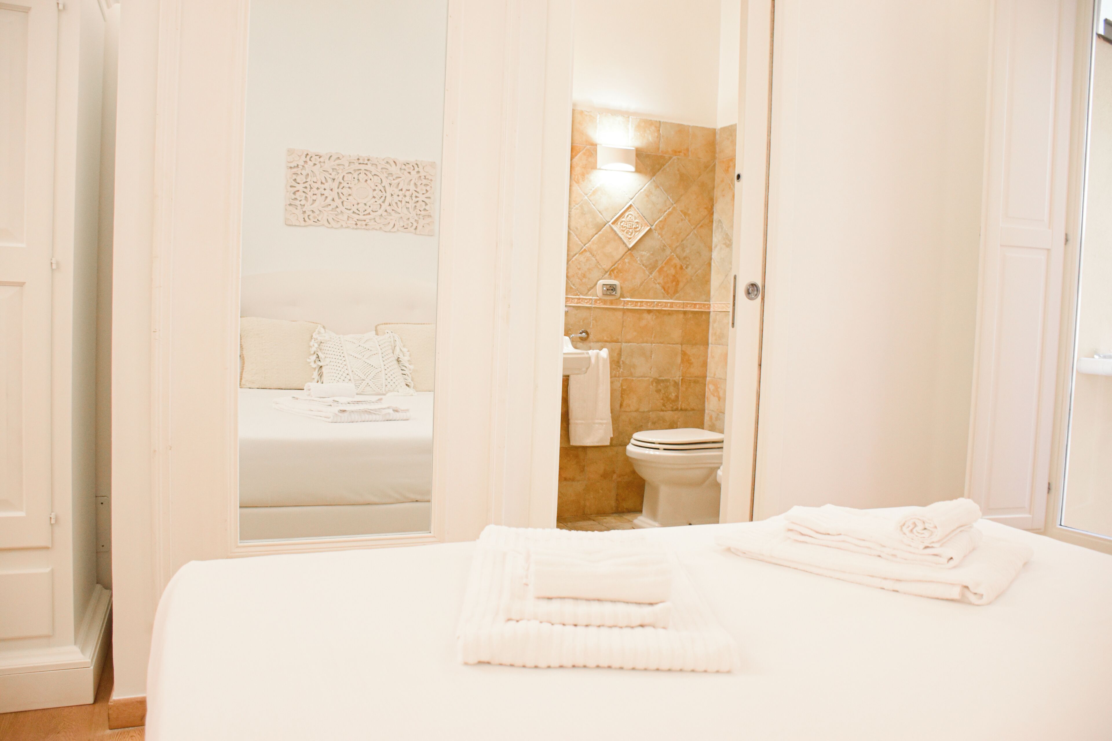 A hotel room with a bed, a bathroom visible through an open door, and a neatly made bed with towels.