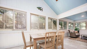 A sunroom with large windows, a dining table with chairs, and a wicker sofa. - Ocean Pines, 3 bedroom, sleeps 6, dog friendly (Ocean Pines)
