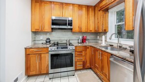 A modern kitchen with wooden cabinets, stainless steel appliances, and a large window. - Ocean Pines, 3 bedroom, sleeps 6, dog friendly (Ocean Pines)