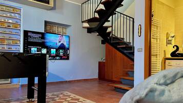 A living room with a TV displaying a streaming service interface, a staircase, and a door leading to another room.