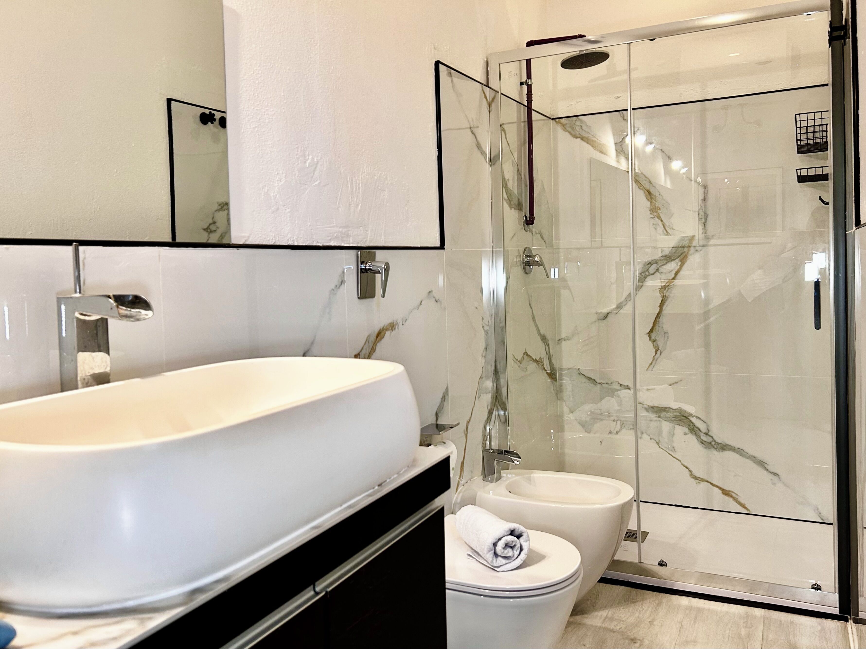 Une salle de bain moderne avec un grand lavabo blanc, une douche à parois de verre et des toilettes.