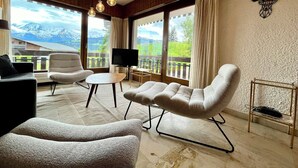 A modern living room with a view of mountains, wooden paneling, and a mounted deer head. - 80 m² apartment with terrace (Combloux)