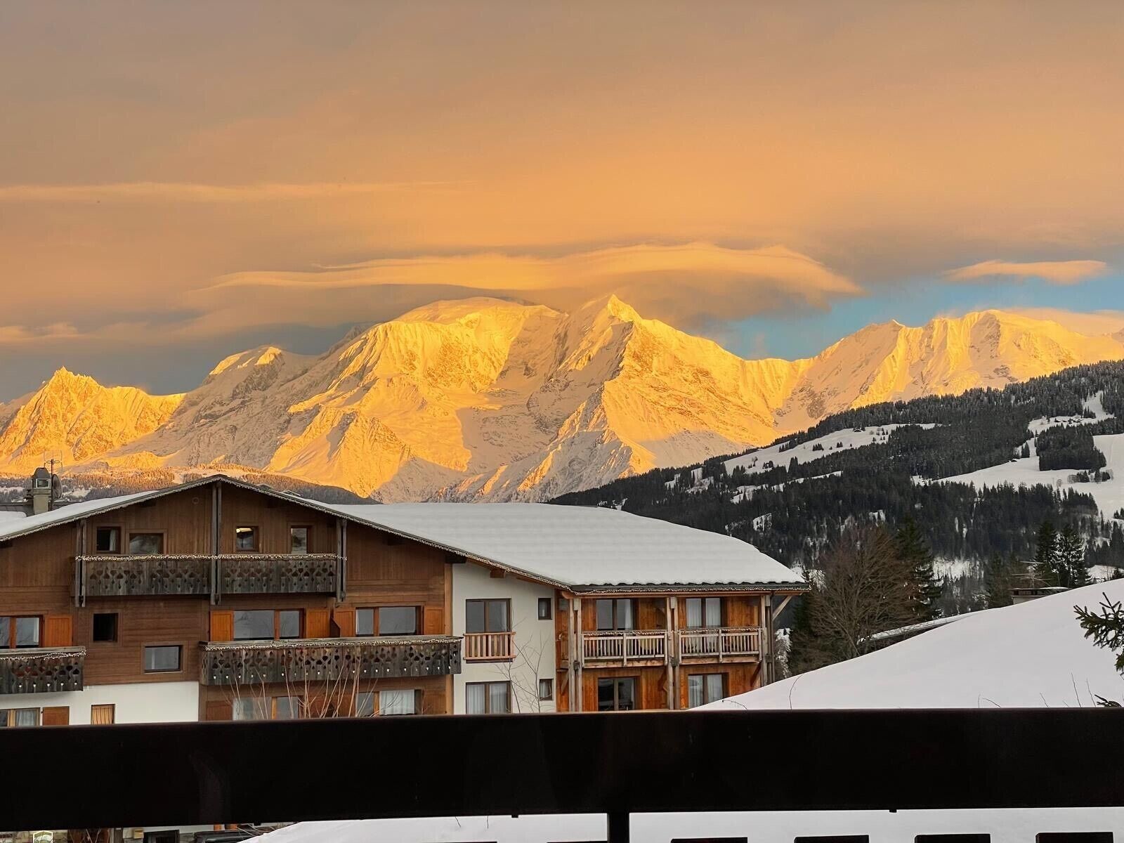 A mountain lodge with a balcony and a view of snow-covered peaks.