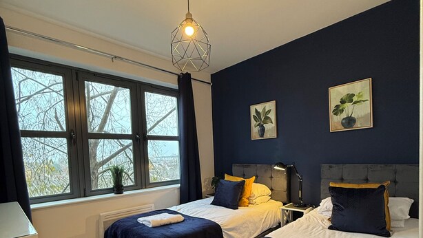 Une chambre avec deux lits, une fenêtre donnant sur un beau paysage, une table de chevet et une lampe.