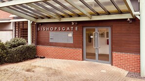 Une entrée d’immeuble avec une enseigne indiquant « BISHOPSGATE », une porte en verre et un escalier en métal.