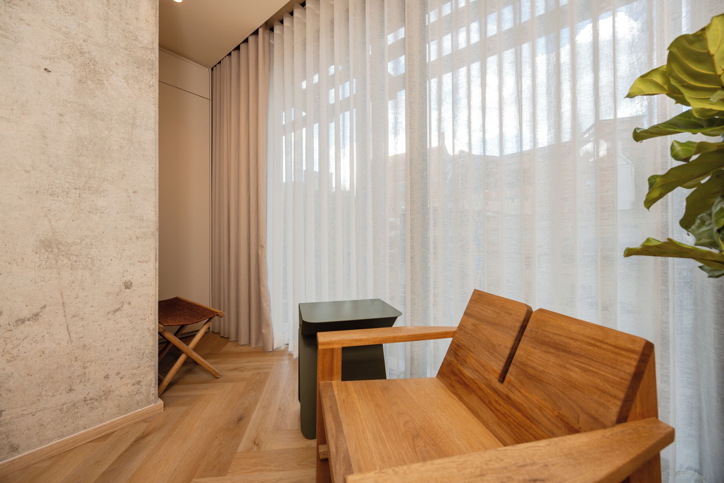 A room with a wooden bench, a small table, and a folding chair.