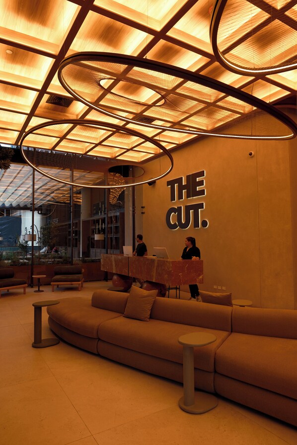 A modern interior with a large sofa, a table, and a person at a podium.