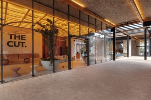 A modern building entrance with glass doors, a wooden ceiling, and potted plants.