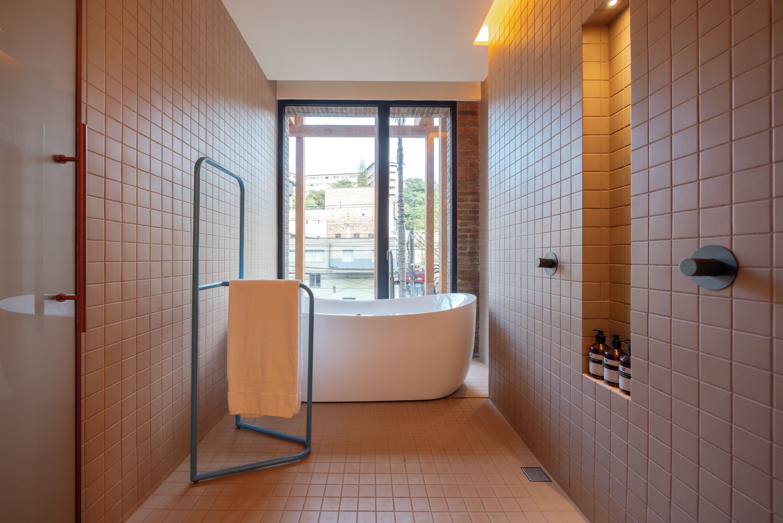 A modern bathroom with a freestanding bathtub, a glass shower enclosure, and a view of the outside.